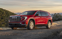 A red suv is parked on the side of a dirt road