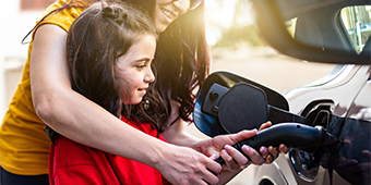 A woman and a child are charging an electric car