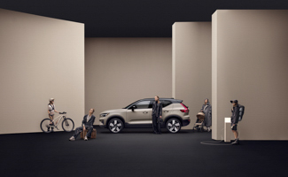 People standing around a tan Volvo EX40 parked inside a tan building